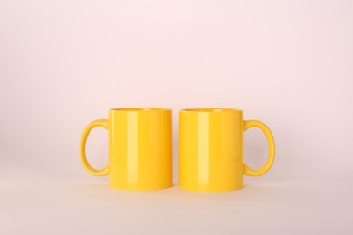Photo of Blank yellow ceramic mugs on light background