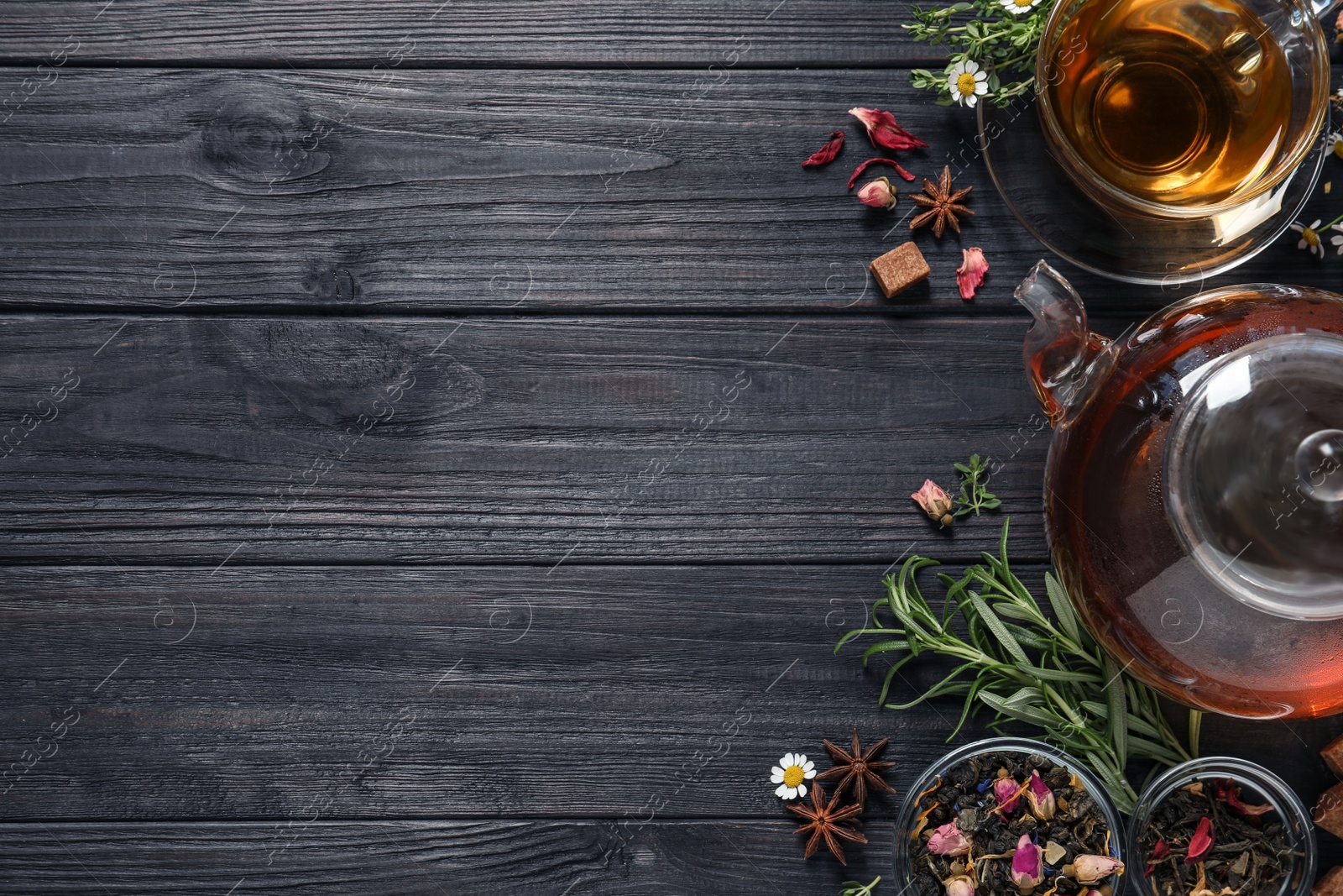 Photo of Flat lay composition with freshly brewed tea and dry leaves on black wooden table. Space for text