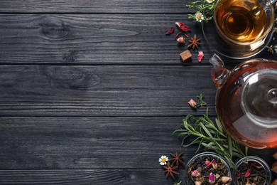 Photo of Flat lay composition with freshly brewed tea and dry leaves on black wooden table. Space for text