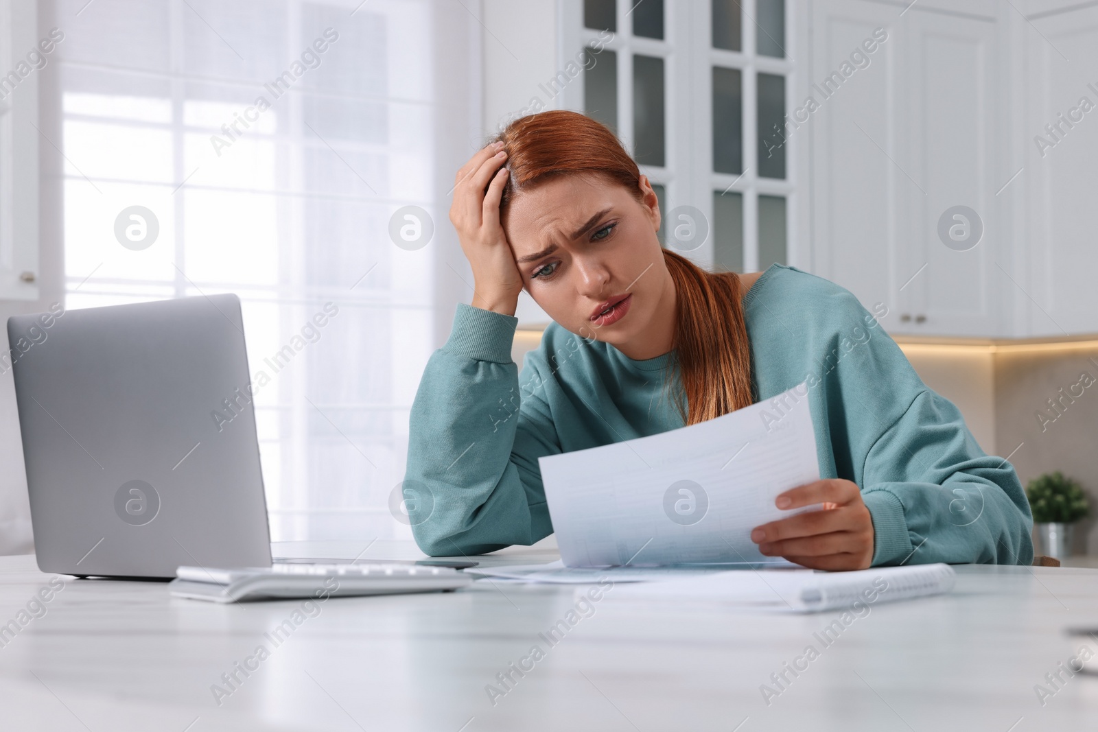 Photo of Woman doing taxes at table in kitchen