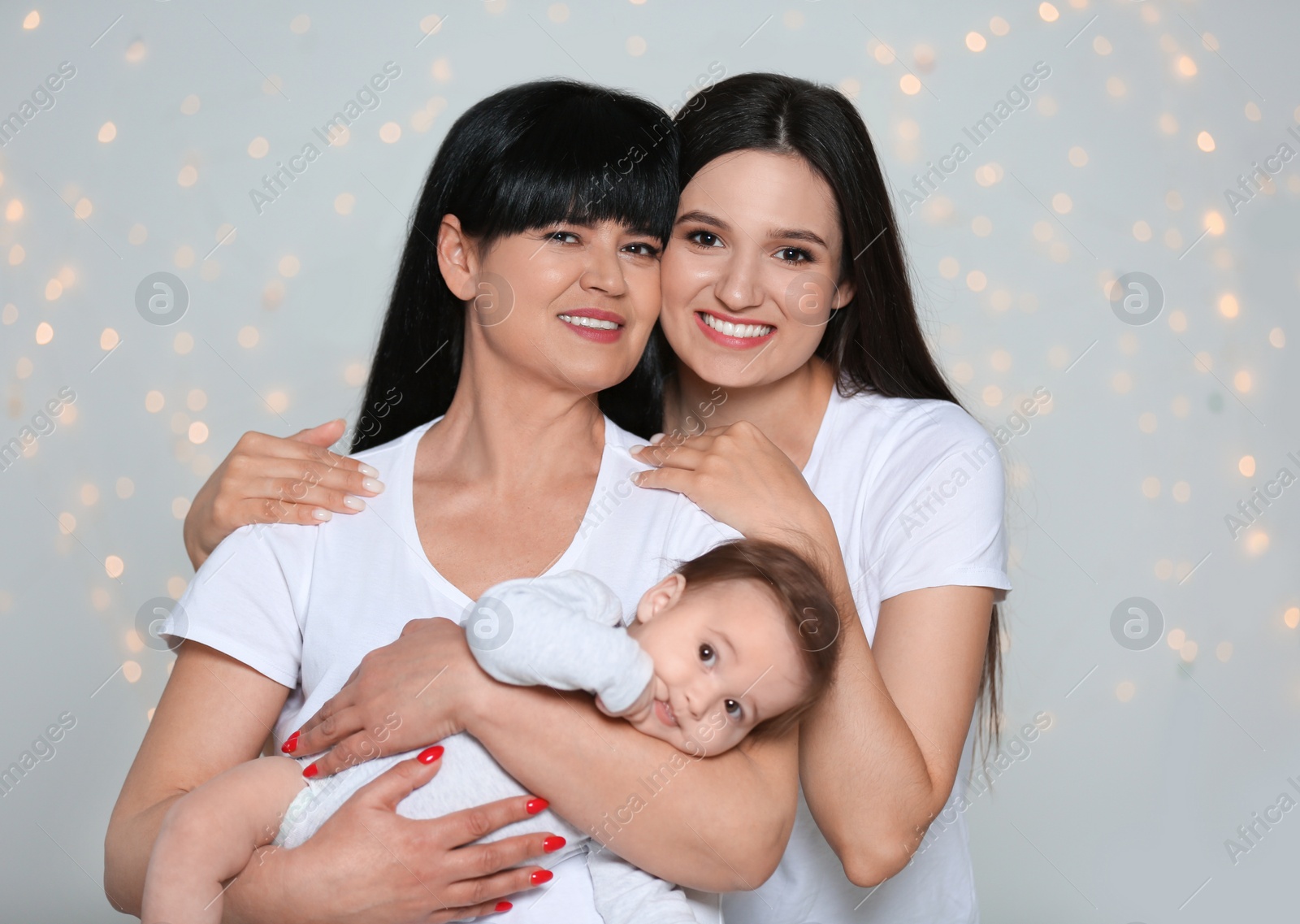 Photo of Portrait of young woman, her baby and mature mother against defocused lights