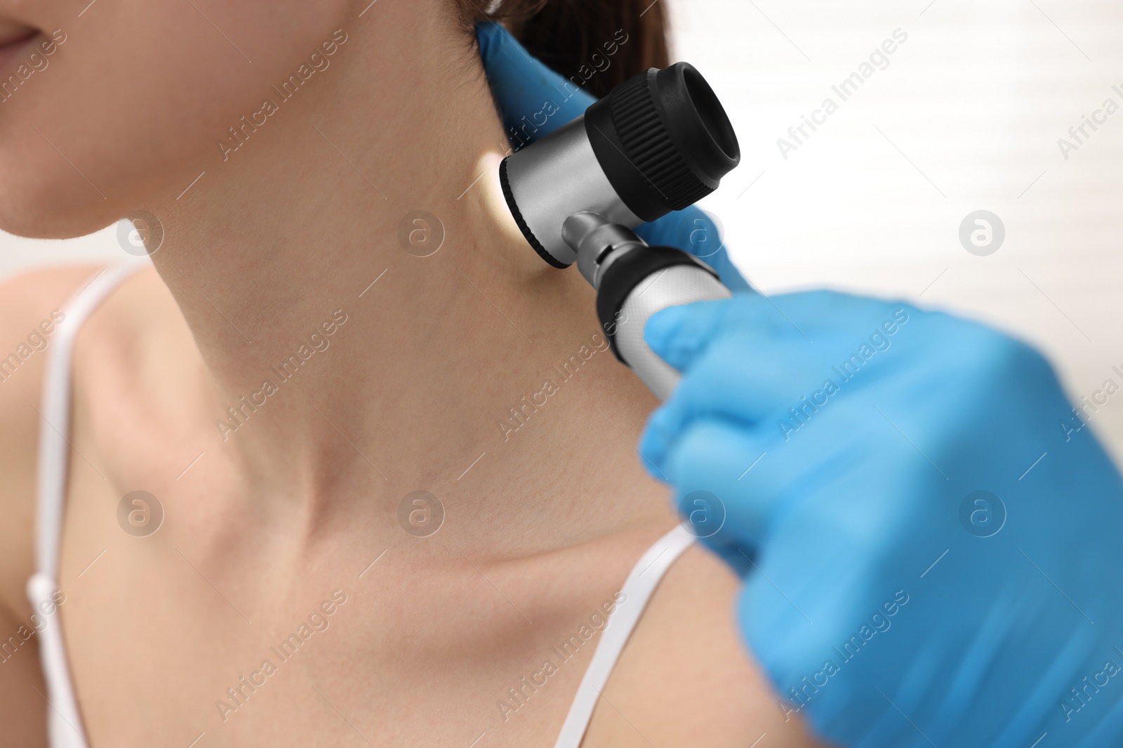 Photo of Dermatologist with dermatoscope examining patient in clinic, closeup