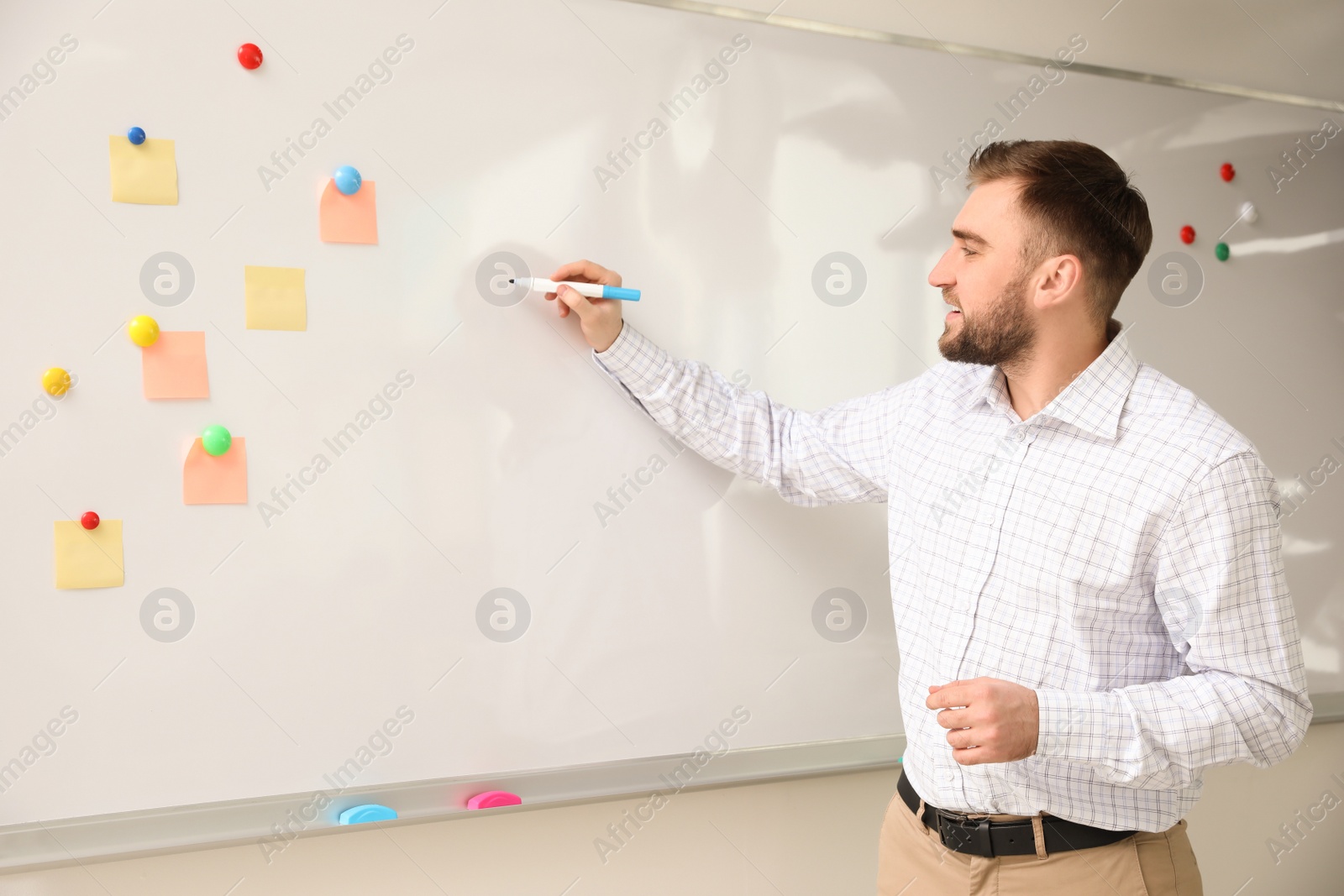 Photo of Portrait of young teacher writing on whiteboard in classroom