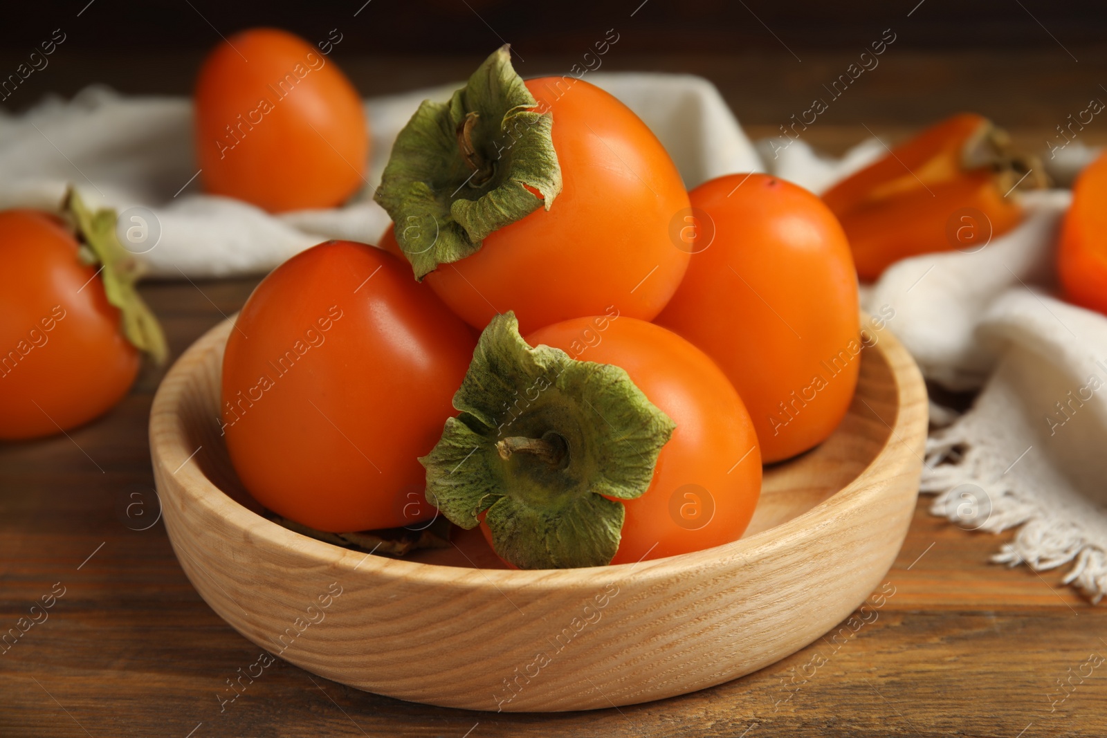 Photo of Tasty ripe persimmons on wooden table, closeup