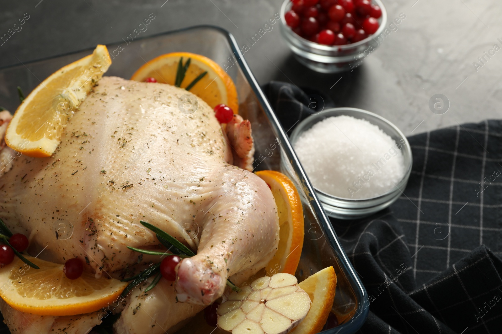 Photo of Chicken with orange slices, rosemary and berries on grey table