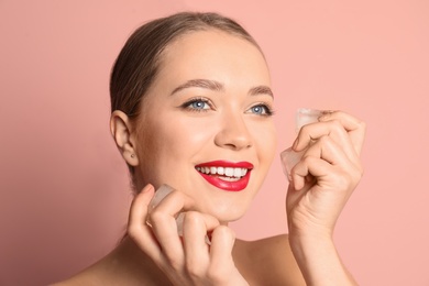 Young woman with ice cubes on color background. Skin care