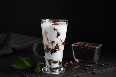 Photo of Glass cup of milk with delicious grass jelly and coffee beans on black table