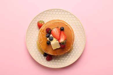 Photo of Delicious pancakes with fresh berries, butter and honey on pink background, top view