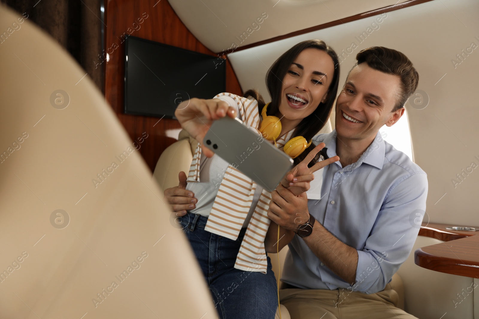Photo of Lovely young couple taking selfie in airplane during flight