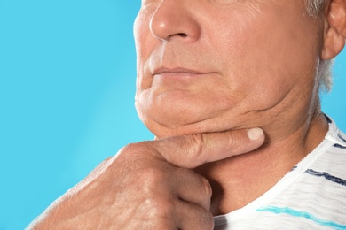 Mature man with double chin on blue background, closeup