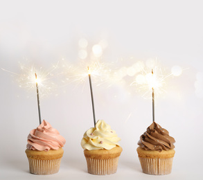 Birthday cupcakes with sparklers on white background