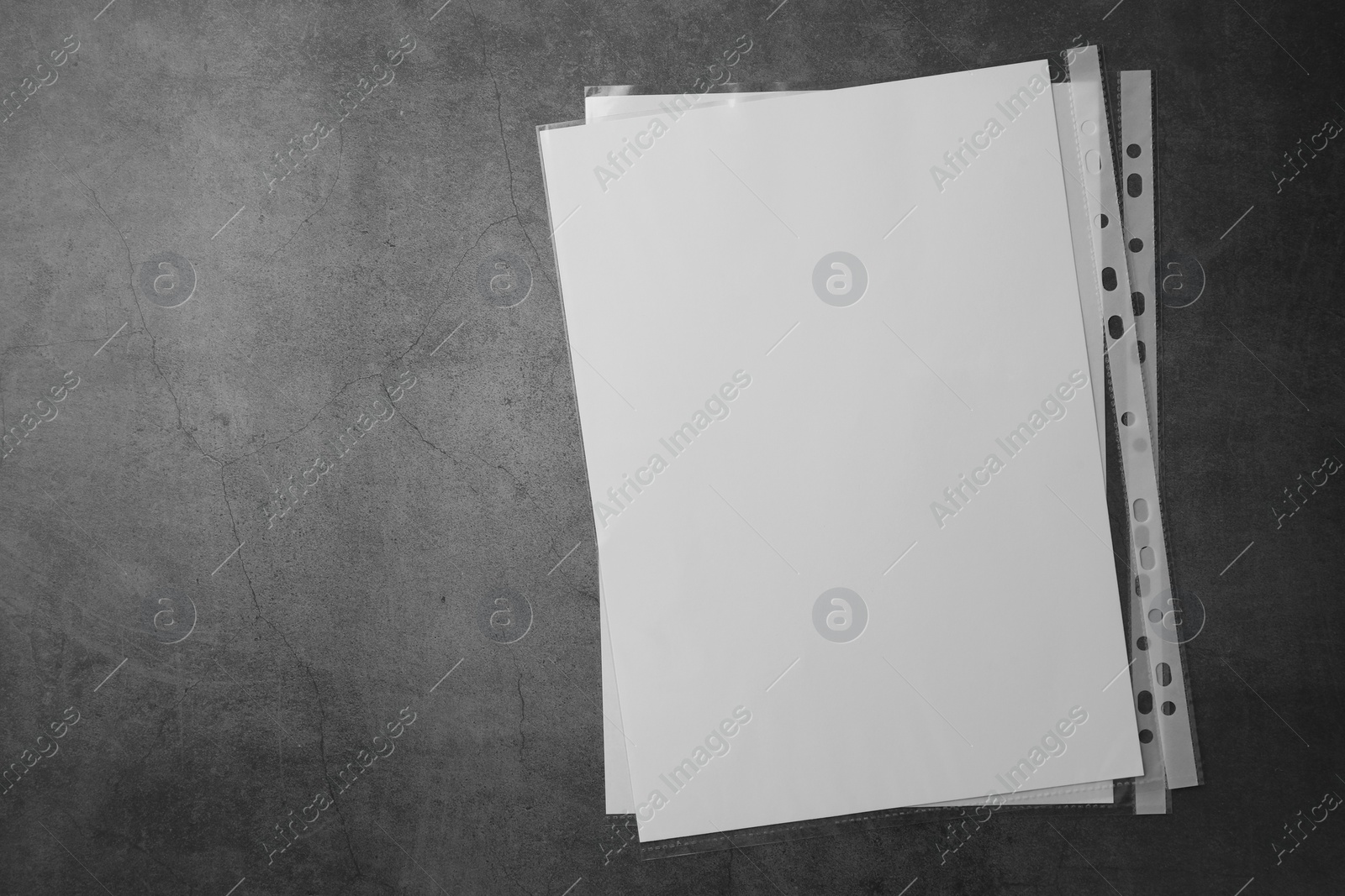 Photo of Punched pockets with paper sheets on grey table, flat lay. Space for text