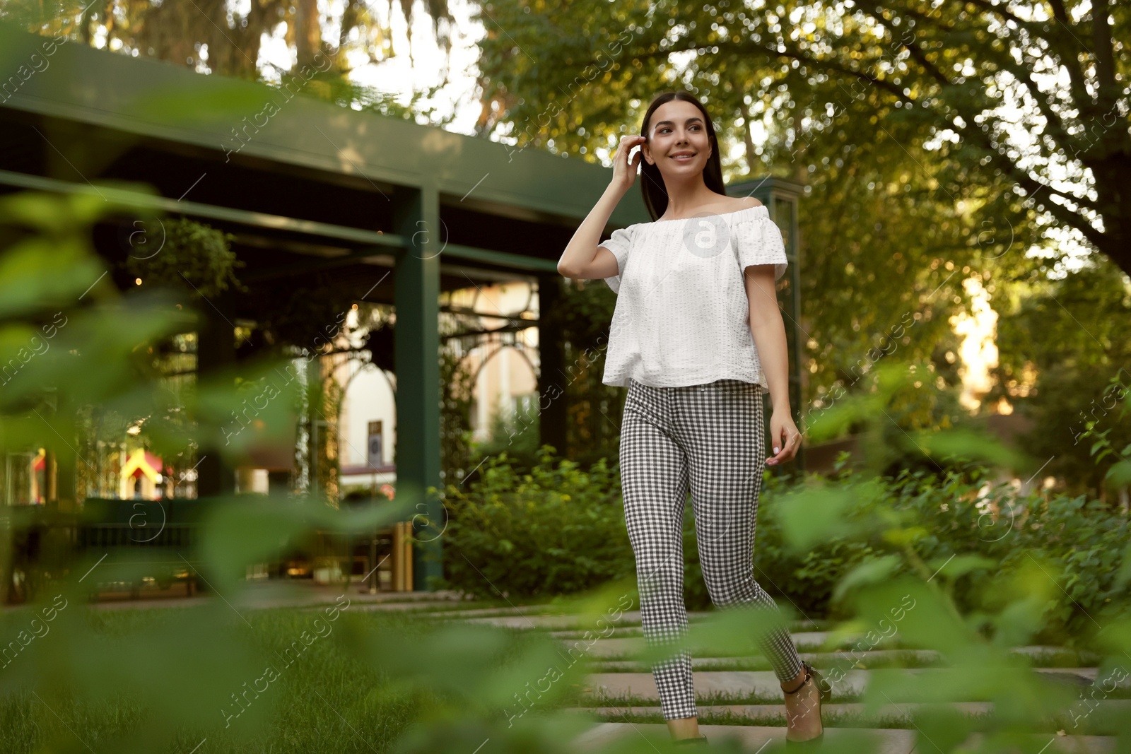 Photo of Beautiful young woman walking in green park, space for text