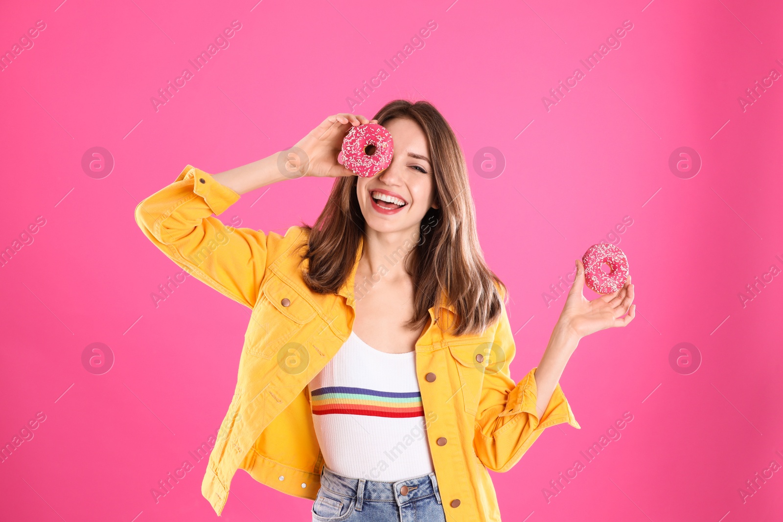 Photo of Beautiful young woman with donuts on pink background