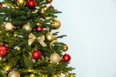 Beautiful Christmas tree with fairy lights and festive decor on white background