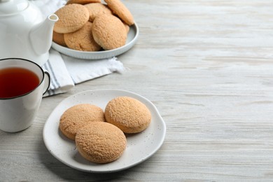 Delicious sugar cookies and cup of tea on white wooden table, space for text