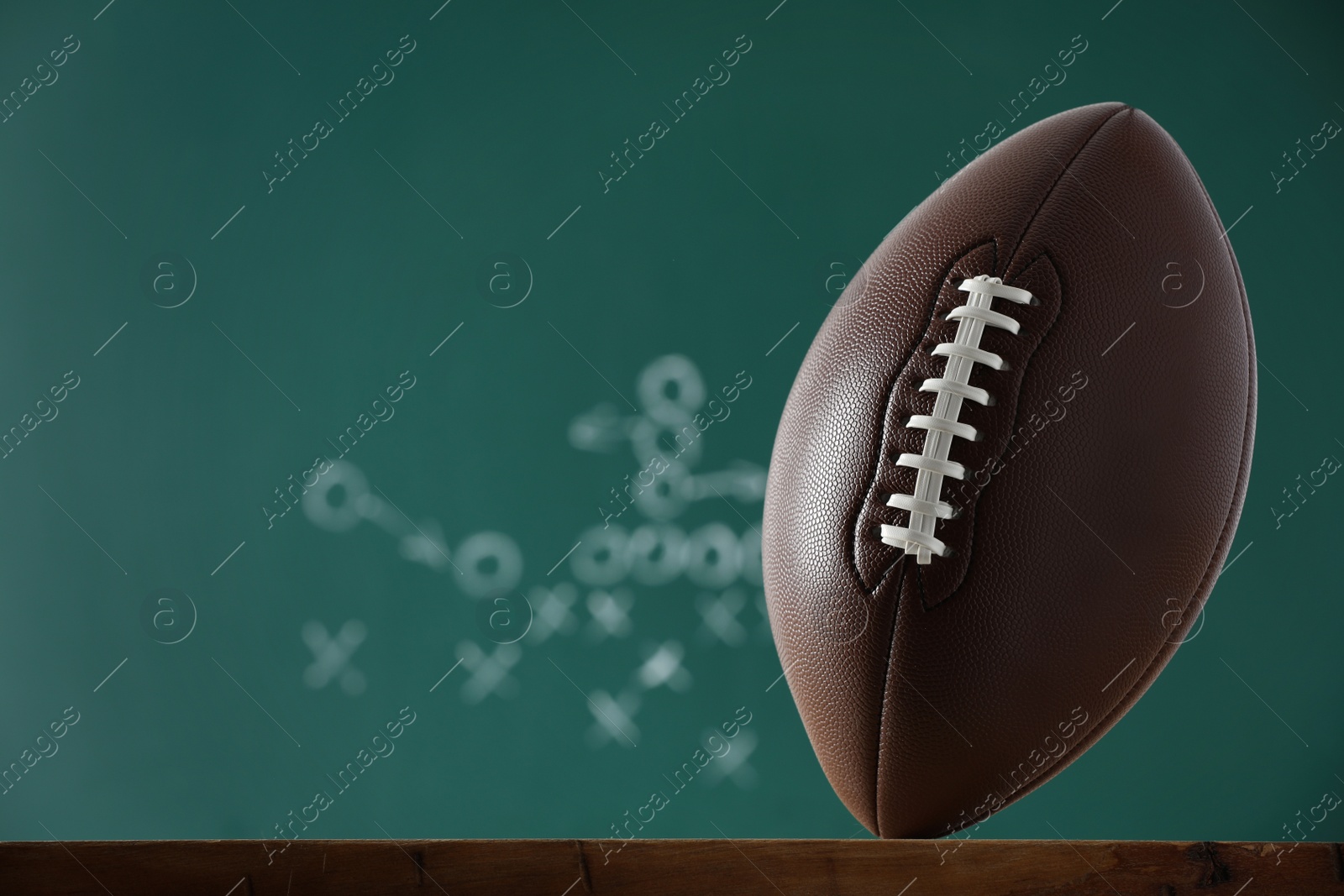 Photo of American football ball against blurred game scheme. Space for text