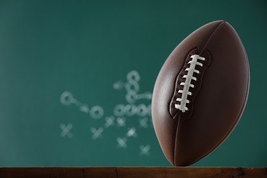 Photo of American football ball against blurred game scheme. Space for text