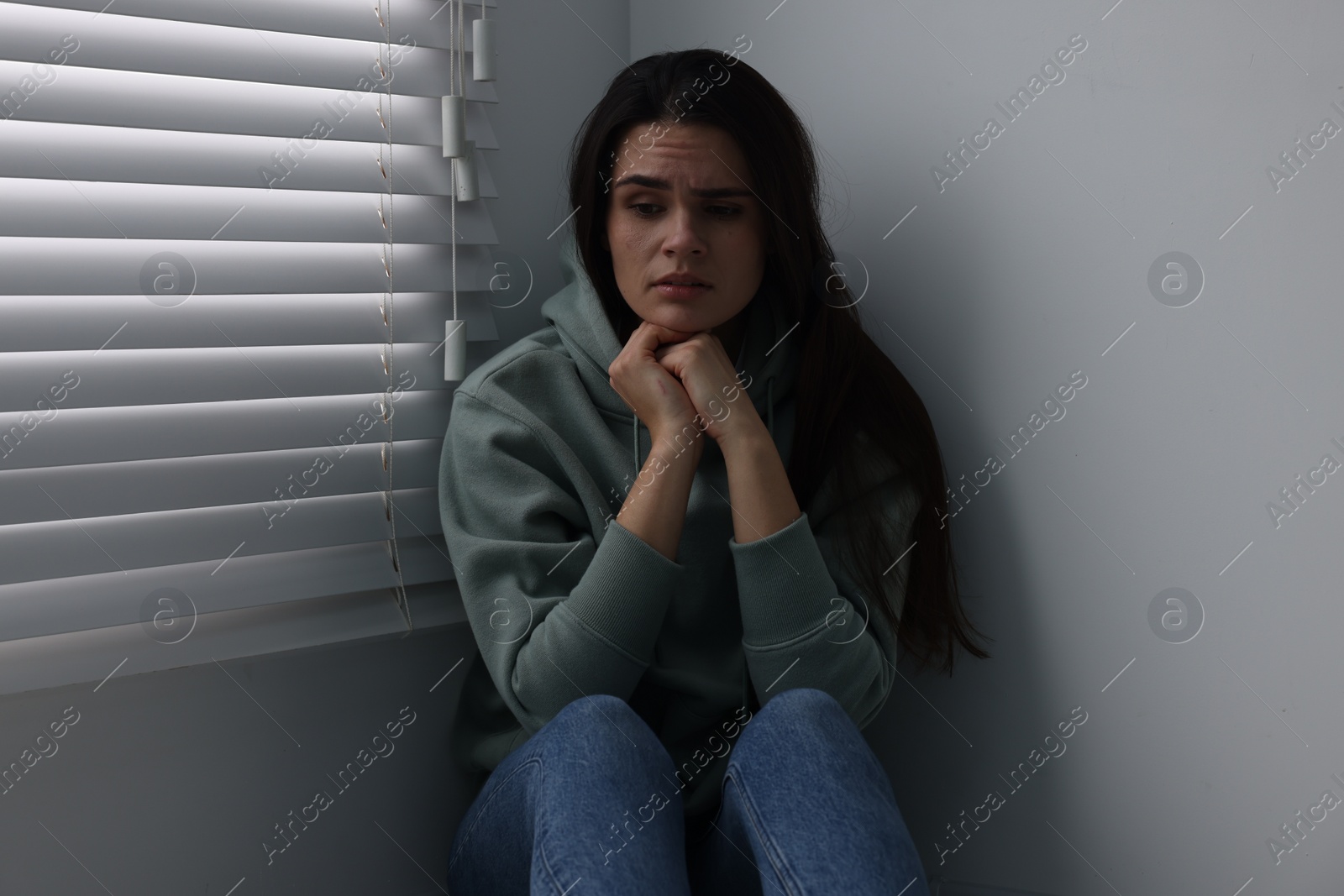 Photo of Sadness. Unhappy woman near window at home