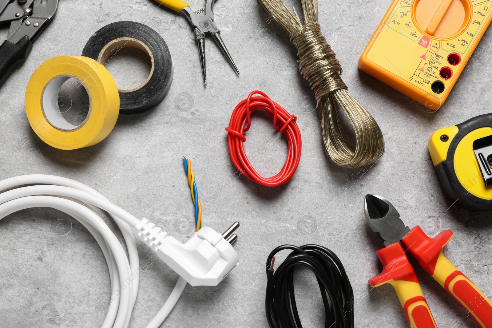 Photo of New wires and electrician's tools on grey table, flat lay