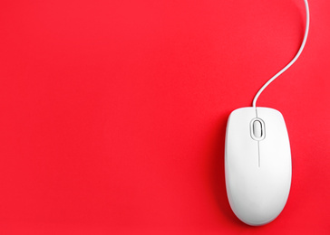 Modern wired optical mouse on red background, top view. Space for text