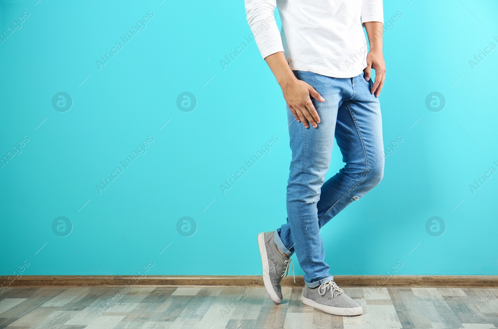 Photo of Young man in stylish jeans near color wall