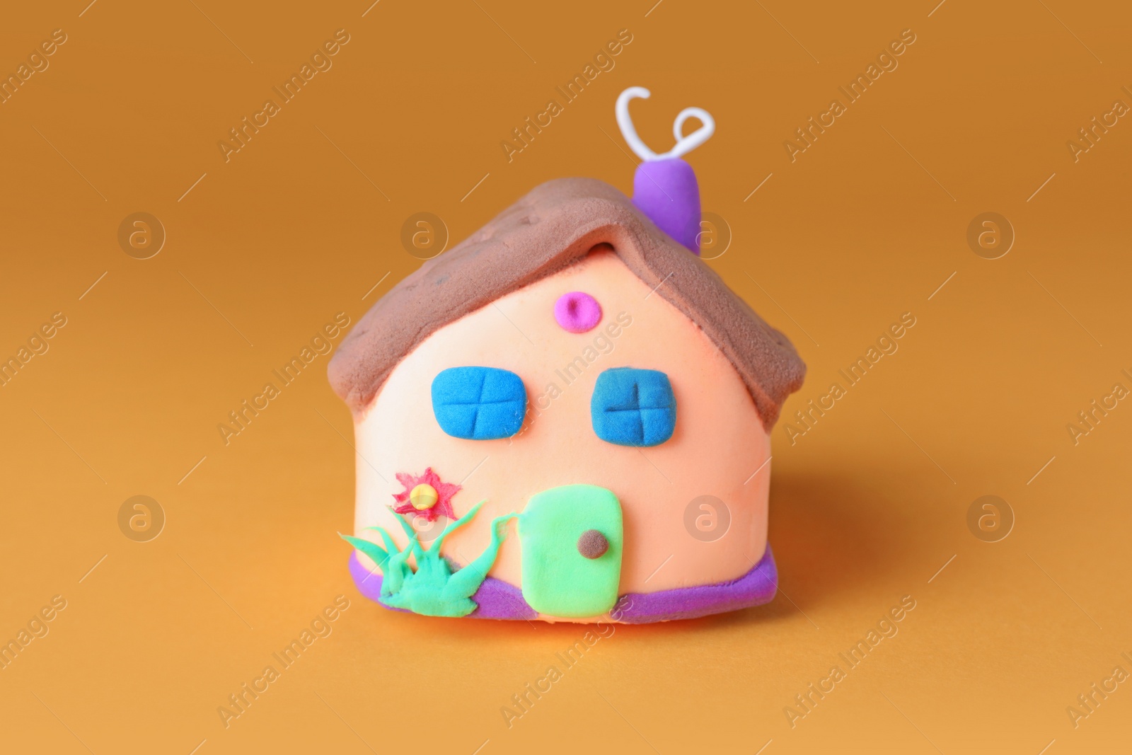 Photo of Small house made from play dough on orange background