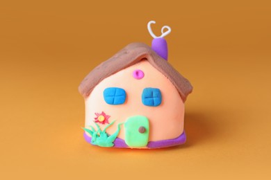 Small house made from play dough on orange background