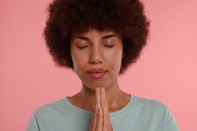 Photo of Woman with clasped hands praying to God on pink background