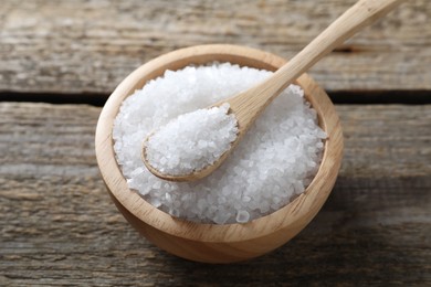 Photo of Organic salt in bowl and spoon on wooden table, closeup