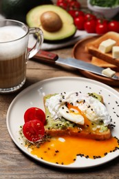 Photo of Delicious toast with poached egg and avocado served on wooden table