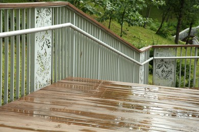 Wet wooden staircase with puddles outdoors. Rainy weather