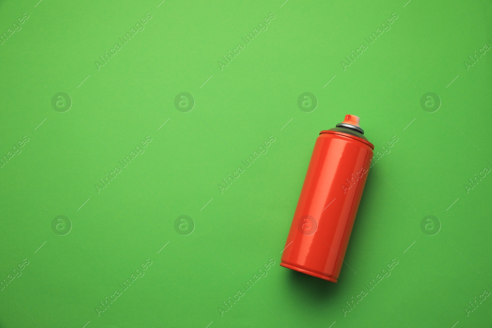 Photo of Can of red graffiti spray paint on green background, top view. Space for text