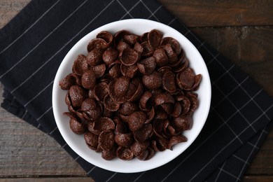 Photo of Chocolate corn flakes in bowl on wooden table, top view. Breakfast cereal