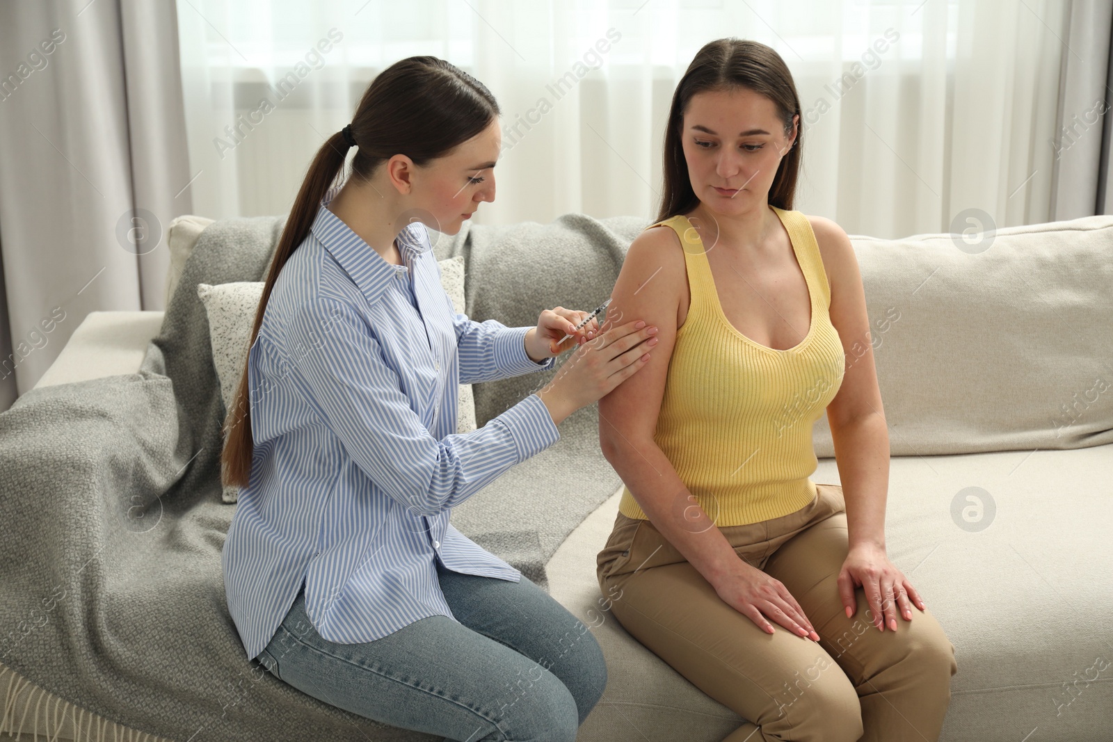 Photo of Woman giving insulin injection to her diabetic friend at home