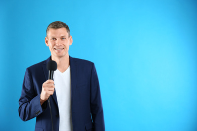 Photo of Male journalist with microphone on blue background. Space for text