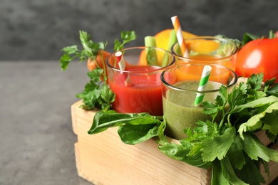 Photo of Delicious vegetable juices and fresh ingredients on grey table, closeup
