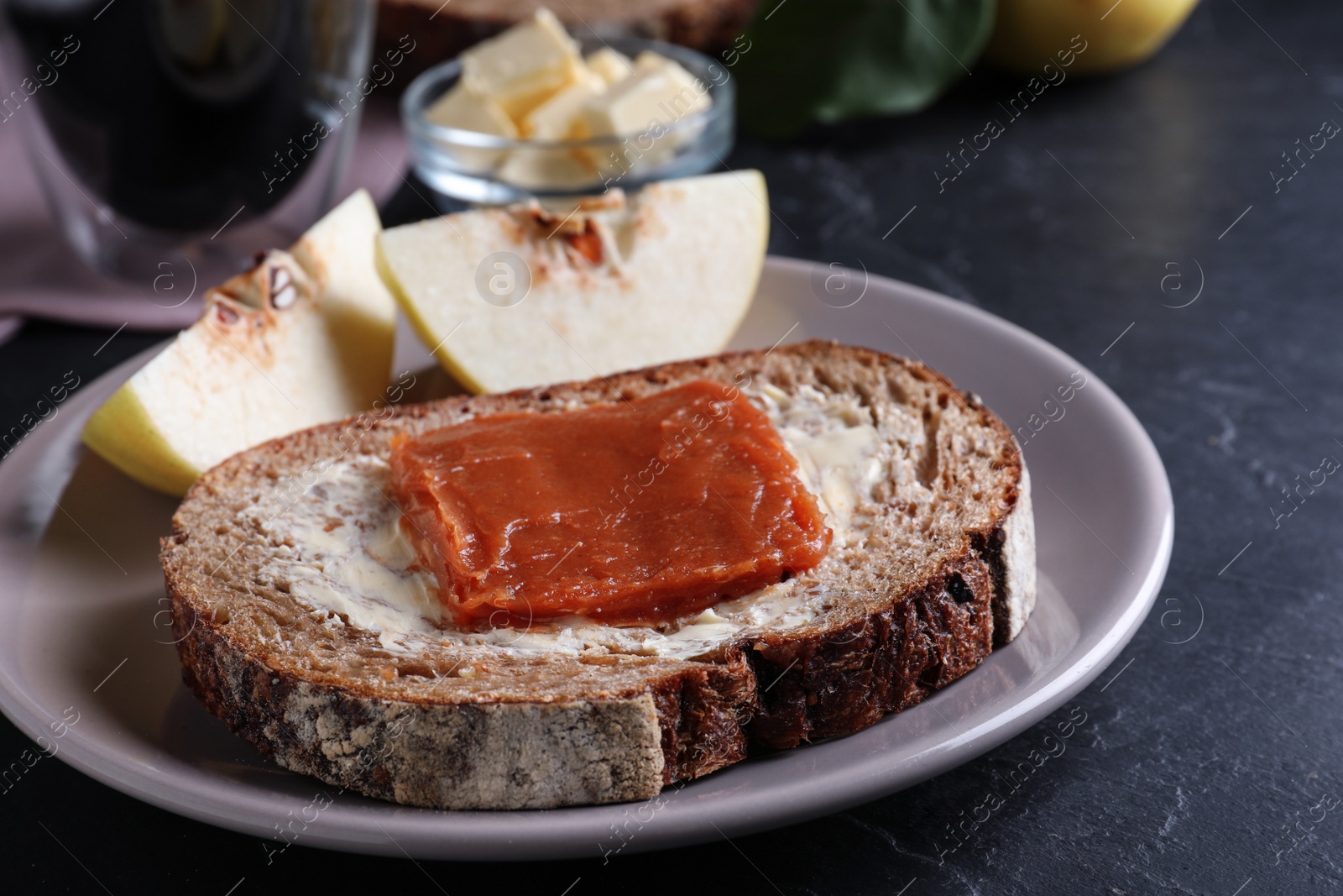 Photo of Bread with delicious quince paste on black table, closeup