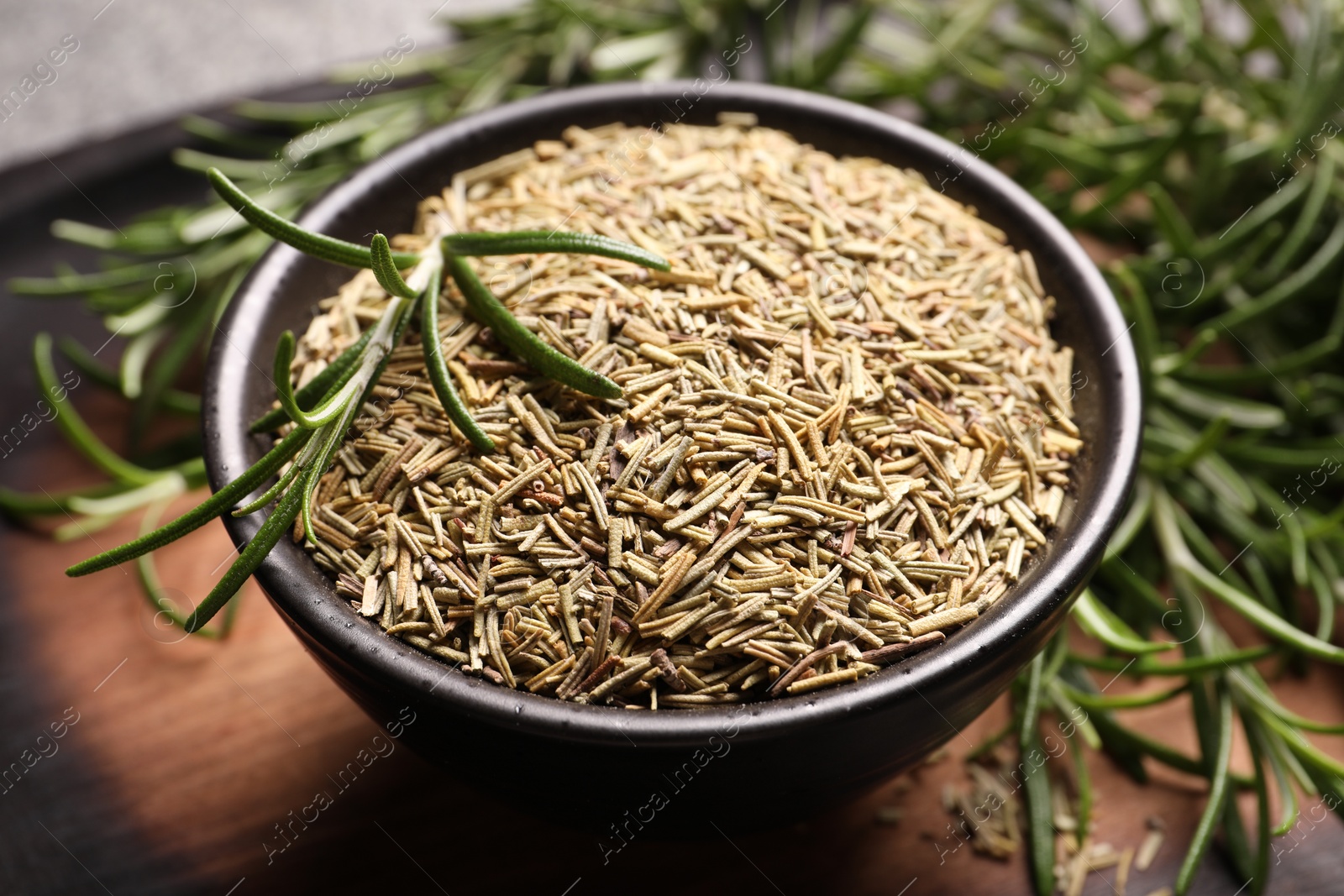 Photo of Bowl with dry and fresh rosemary on table, closeup