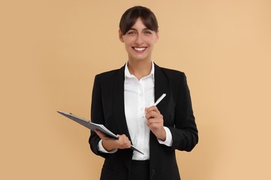 Happy secretary with clipboard and pen on beige background