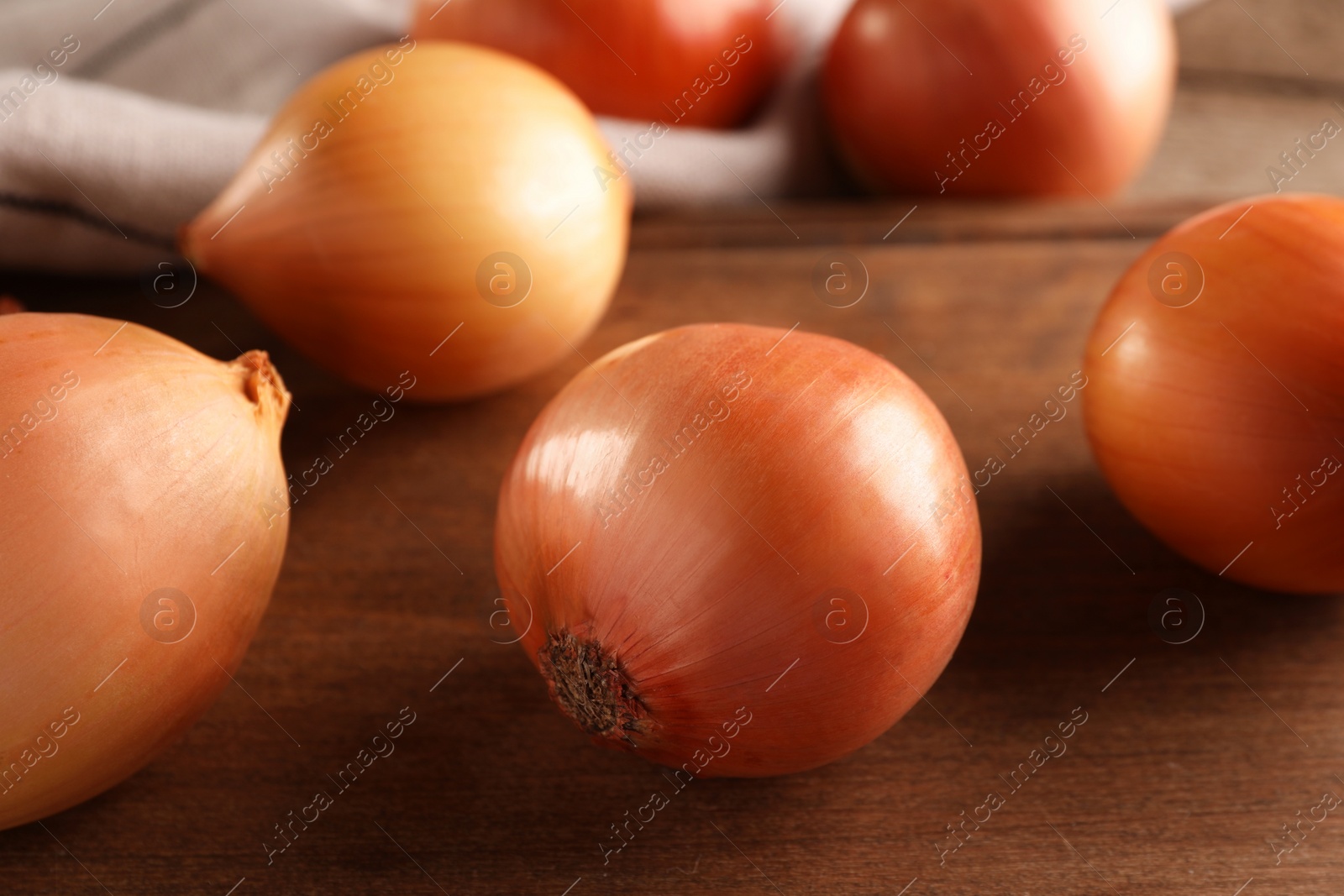 Photo of Many ripe onions on wooden table, closeup