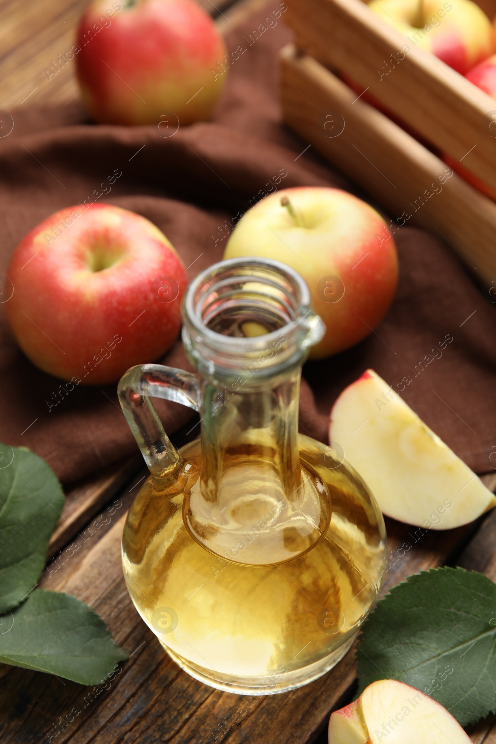 Photo of Natural apple vinegar and fresh fruits on wooden table