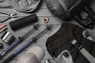 Photo of Flat lay composition with trekking poles and other hiking equipment on grey wooden background