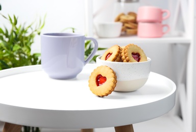 Photo of Traditional Christmas Linzer cookies with sweet jam and bowl on table