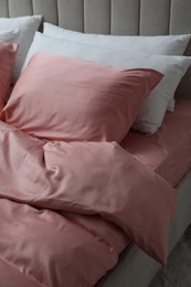 Bed with beautiful pink silk linens indoors