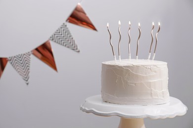 Delicious cake with cream and burning candles on light grey background. Space for text