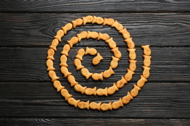 Delicious goldfish crackers on black wooden table, flat lay