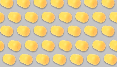Image of Mykolaiv, Ukraine - June 26, 2023: Yellow plastic capsule from Kinder Surprise Egg on grey background, seamless pattern design