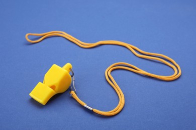 Photo of One yellow whistle with cord on blue background