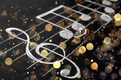 Image of Christmas and New Year music. Chalked music notes on blackboard, bokeh effect